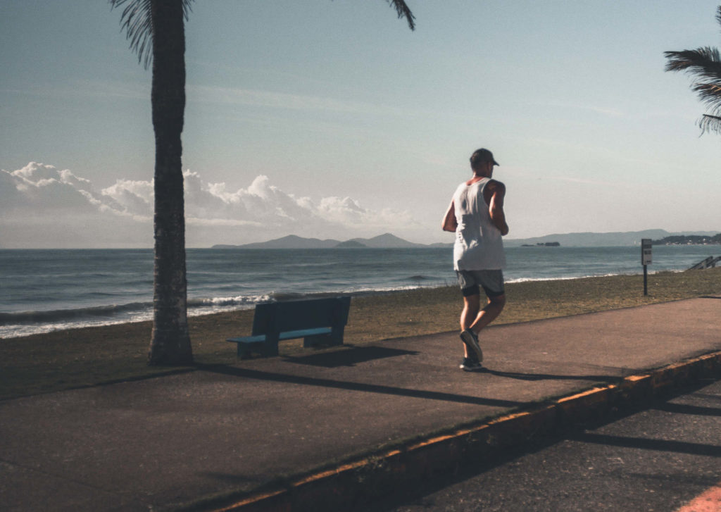 Man running on the beach with palm trees